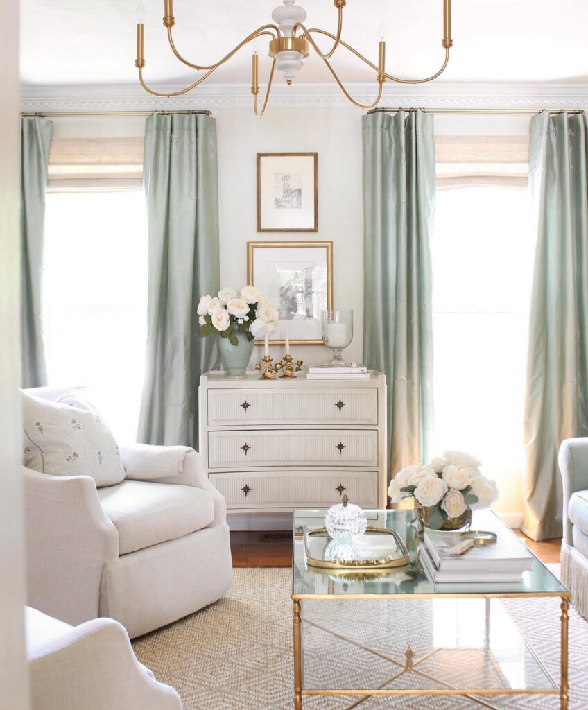 Gentle pastels, skirted chairs, and a glass coffee table form a cozy french country living room with feminine details.