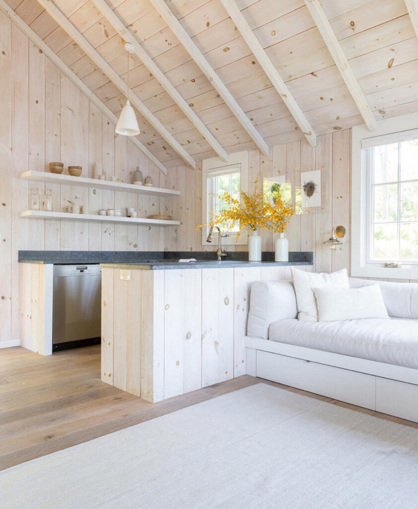 whitewashed pine walls compact counter open shelves airy small lake house kitchen beside built in sofa