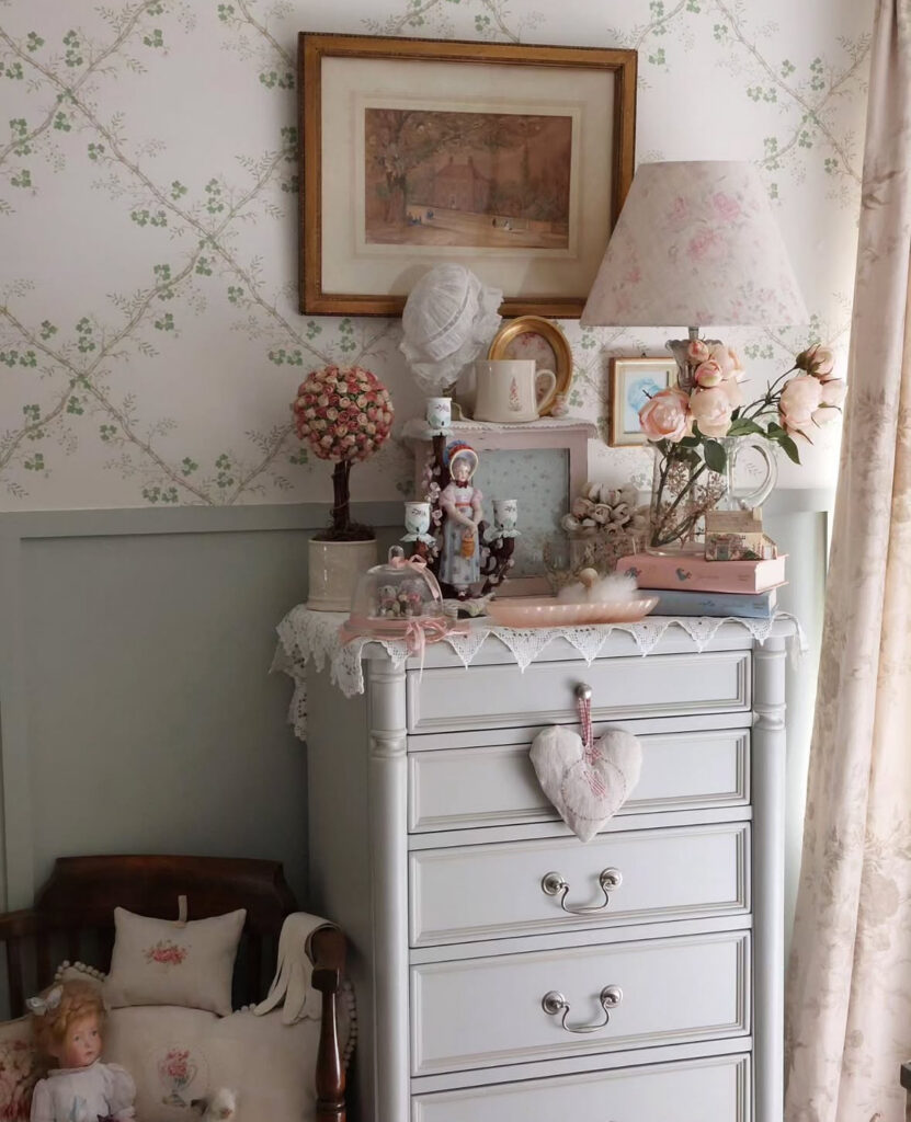 Vintage dresser with floral wallpaper, framed art, and hearts used as shabby chic bedroom wall decor.
