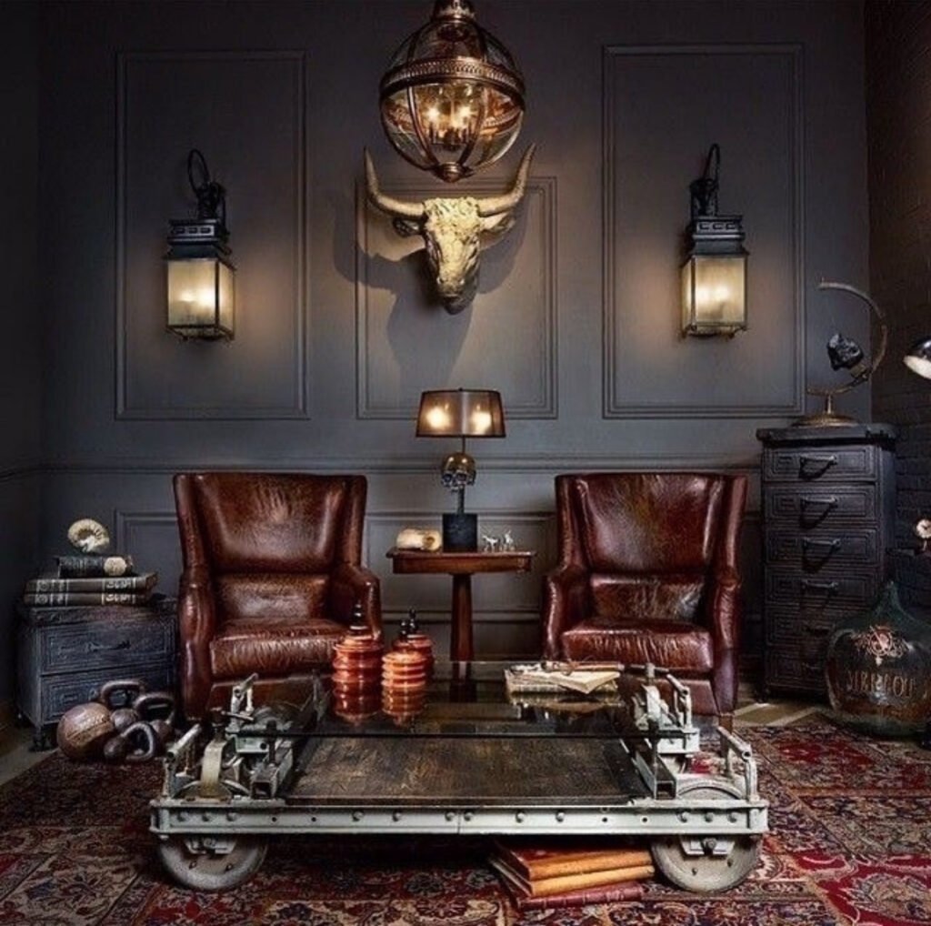 Vintage leather chairs, an industrial cart coffee table, and layered rugs create cozy man cave ideas in a dark moody lounge.