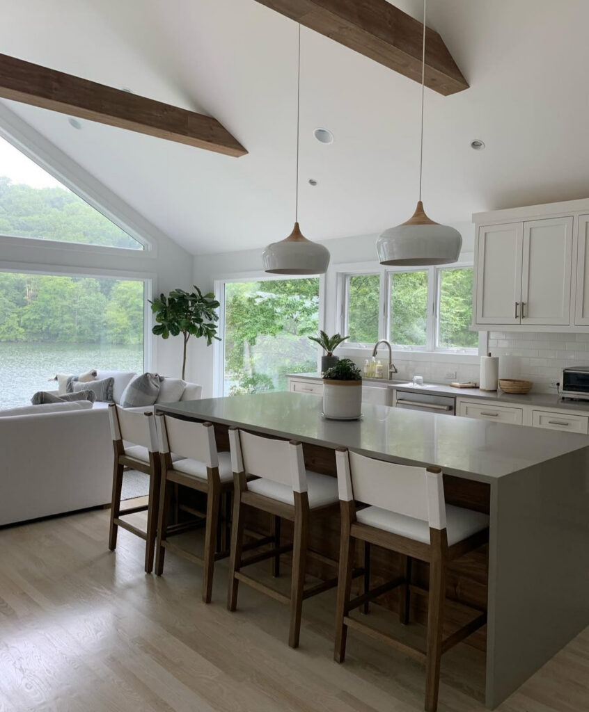 island seating facing panoramic lake views vaulted ceiling wood beams open concept lake house kitchen