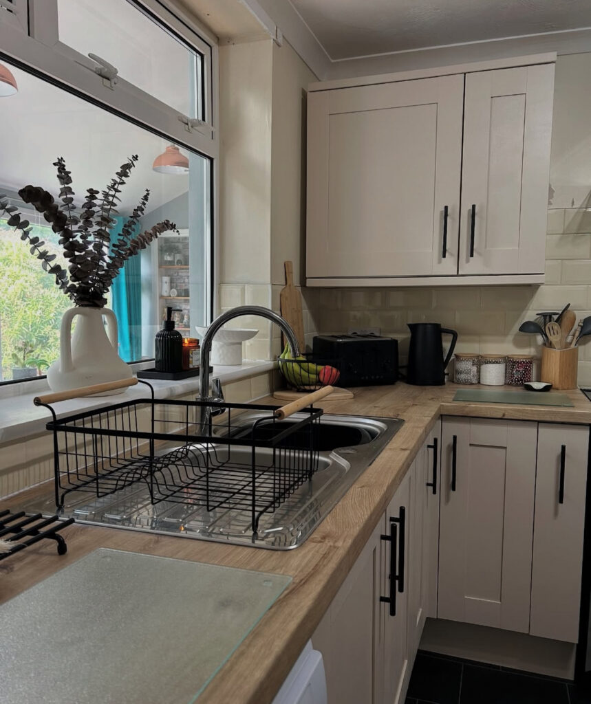 Light U-shaped kitchen with painted neutral cabinets, wood-look worktops and matte black handles finished by @everythingnatalie_.