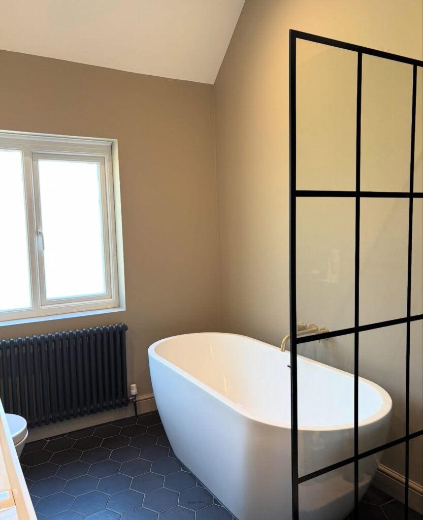 Beige-toned bathroom with black radiator and shower grid frame showing a black accent bathroom.