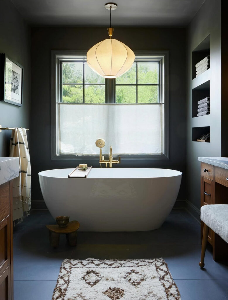 Charcoal-toned bath with brass fixtures and white tub capturing warm black bathroom ideas.