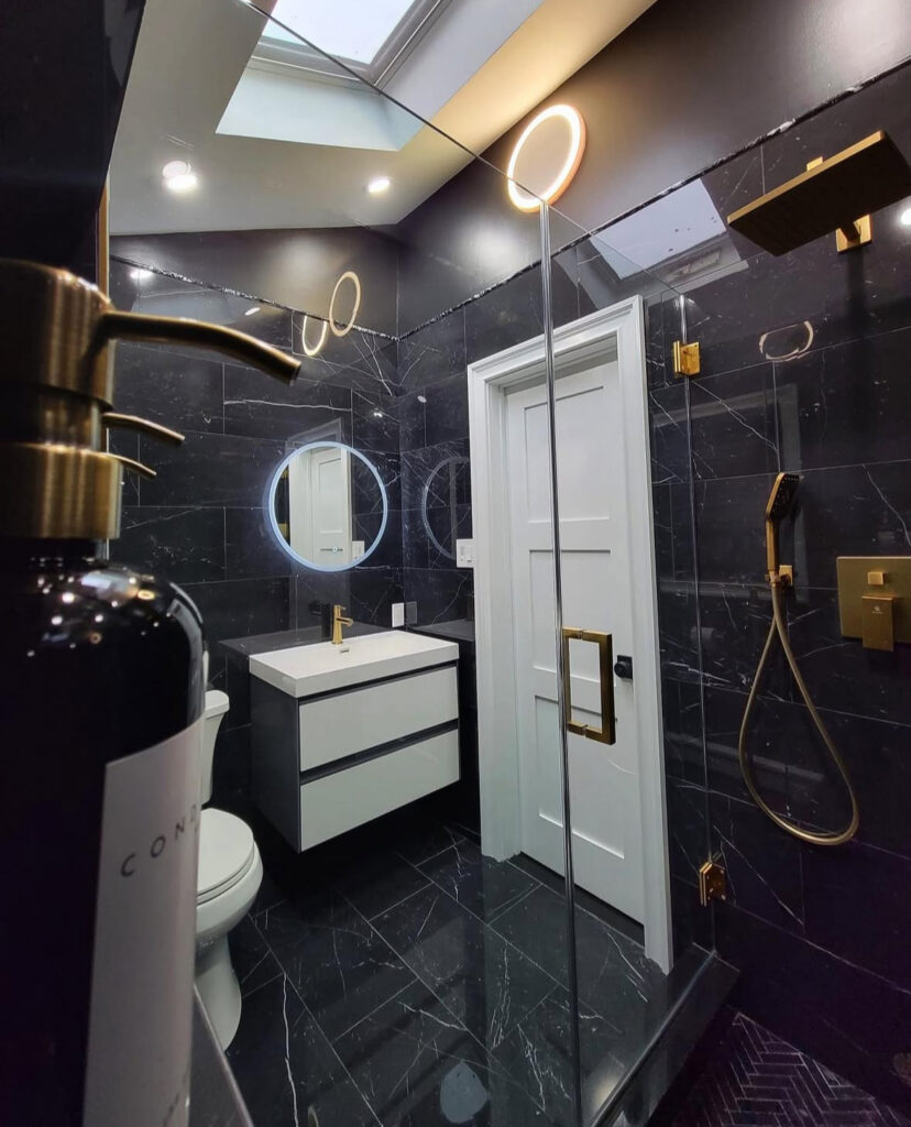 Glossy black tiled bathroom with ring mirrors and skylight showing black bathroom lighting inspiration.