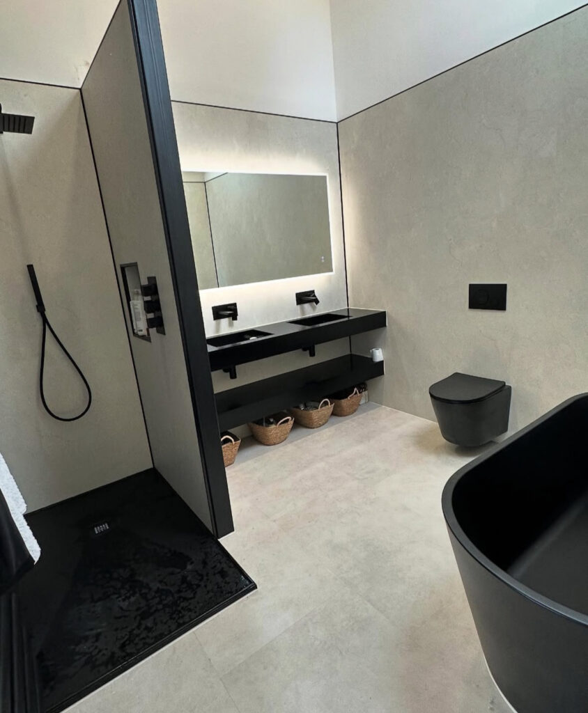 Pale bathroom with black vanity and under-counter baskets highlighting black bathroom storage solutions.
