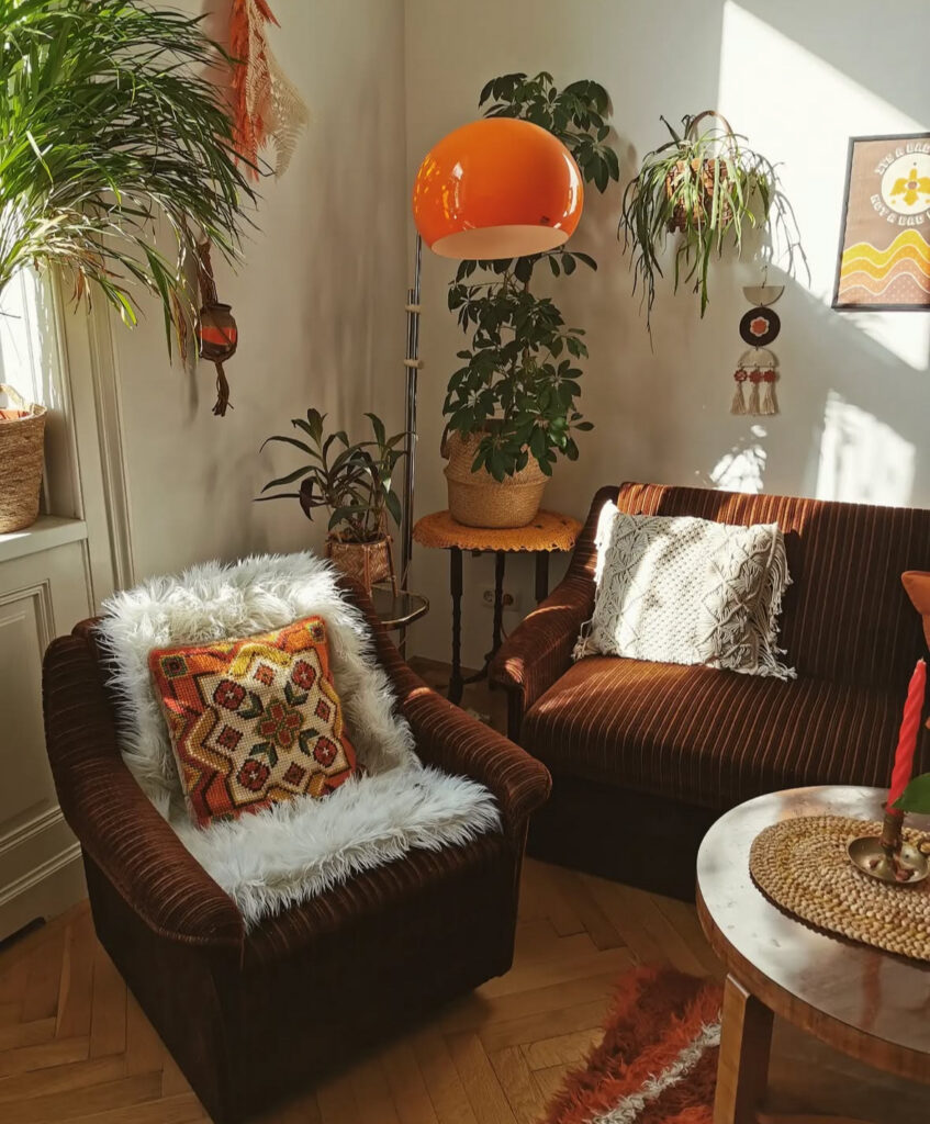 Corner of a 70s decor living room with ribbed brown armchair, shaggy throw, orange mushroom lamp and hanging plants.