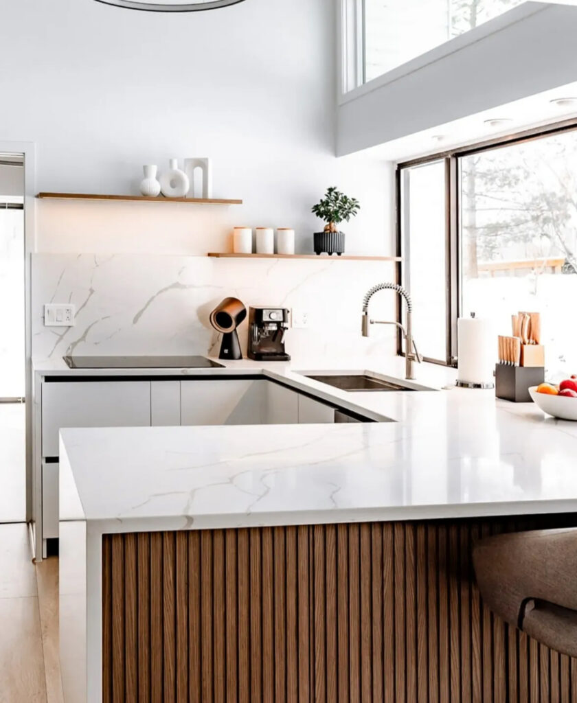 Cornerrenovation’s Rochester kitchen with ribbed wood island, marble-look countertops, and sleek fittings, a bright clean lines kitchen in Scandinavian style.