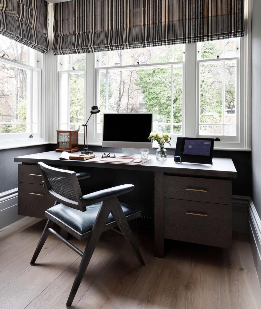 Dark wood desk with drawers set in front of big windows and striped shades, compact desk solutions done beautifully.