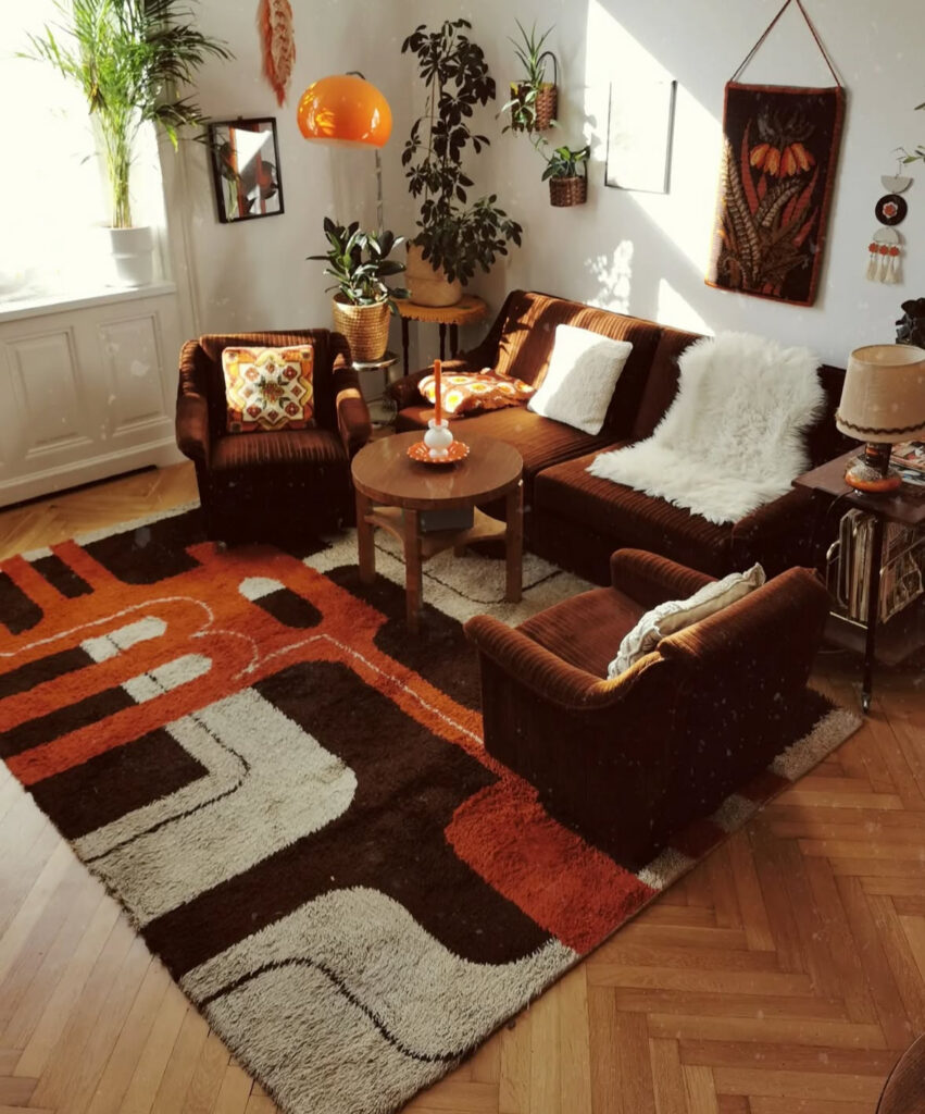Cozy 70s style living room decor with chocolate corduroy chairs, geometric shag rug and hanging plants.
