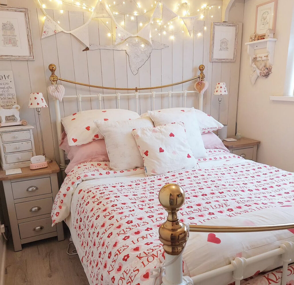 Vintage-inspired cottage bedroom with heart-print bedding and fairy lights offering cozy valentines day bedroom ideas.
