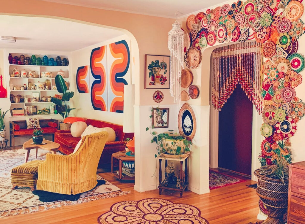 Maximalist retro 70s living room filled with colorful crocheted wall art, beaded doorway, patterned textiles and collectibles.