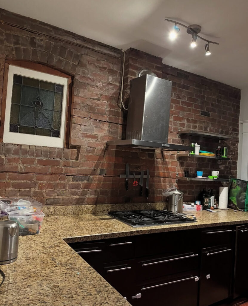 Brick loft kitchen shell with exposed brick, visible pipes and basic units before custom cabinetry and finishes by @dartstudioinc.