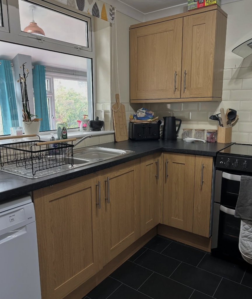 U-shaped kitchen with orangey oak cabinets and dark laminate worktops before the DIY kitchen remodel by @everythingnatalie_.
