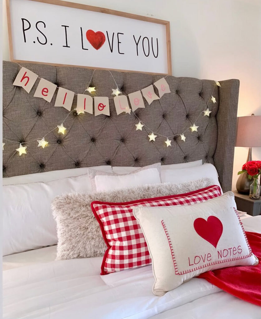 Bed with tufted headboard, fairy lights, and “Love Notes” pillows showing how to decorate a bedroom for valentines day with charm.