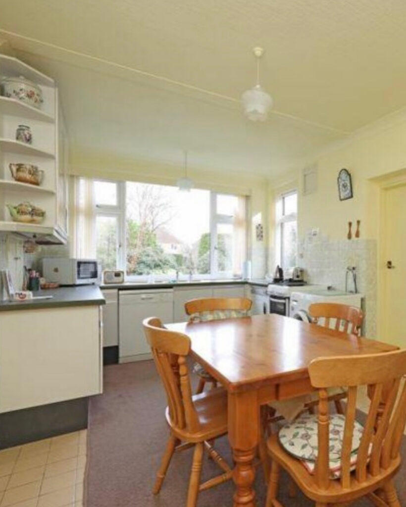 Dated kitchen-diner with carpet under the table, yellowed walls and basic cabinets before the new functional kitchen layout by @ourluxehome_.