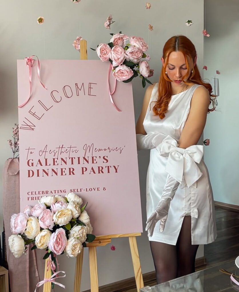 Welcome sign and table décor setup for a Galentine’s dinner party with pink and floral details