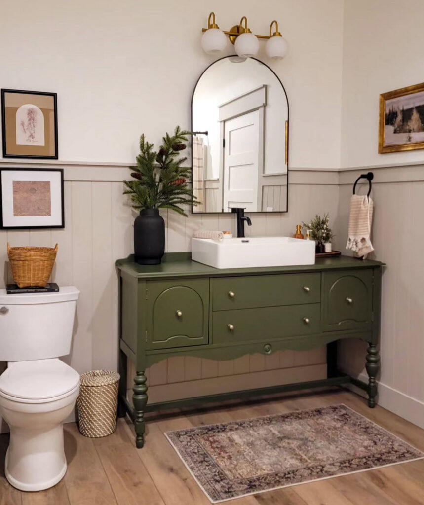 Cottage-style room featuring a painted buffet repurposed as a vintage bathroom vanity with arched mirror and wall art.

