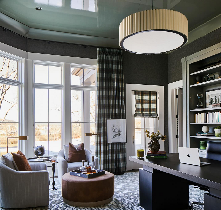 Luxe home office with a large drum pendant light, big windows, a desk, and a cozy seating area