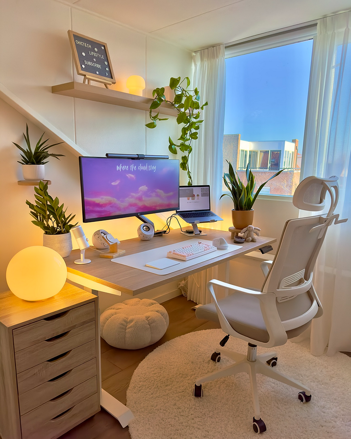 Cozy desk corner with sheer curtains, multiple plants, warm globe lamps, and a white ergonomic chair.