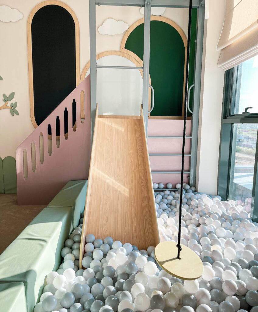 Indoor playroom ball pit with a slide and swing creating a contained active play zone.