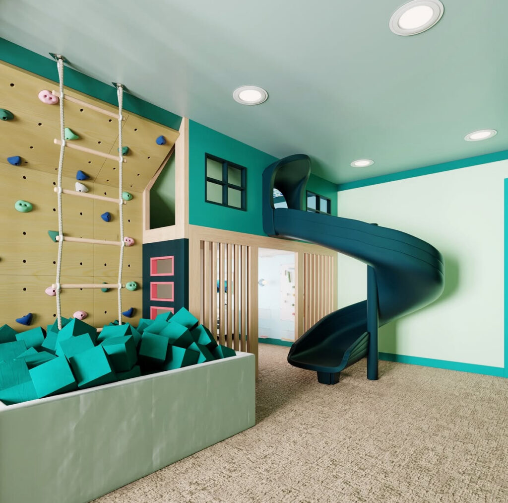 Indoor playroom with a foam pit, climbing wall, and slide for active play zoning.