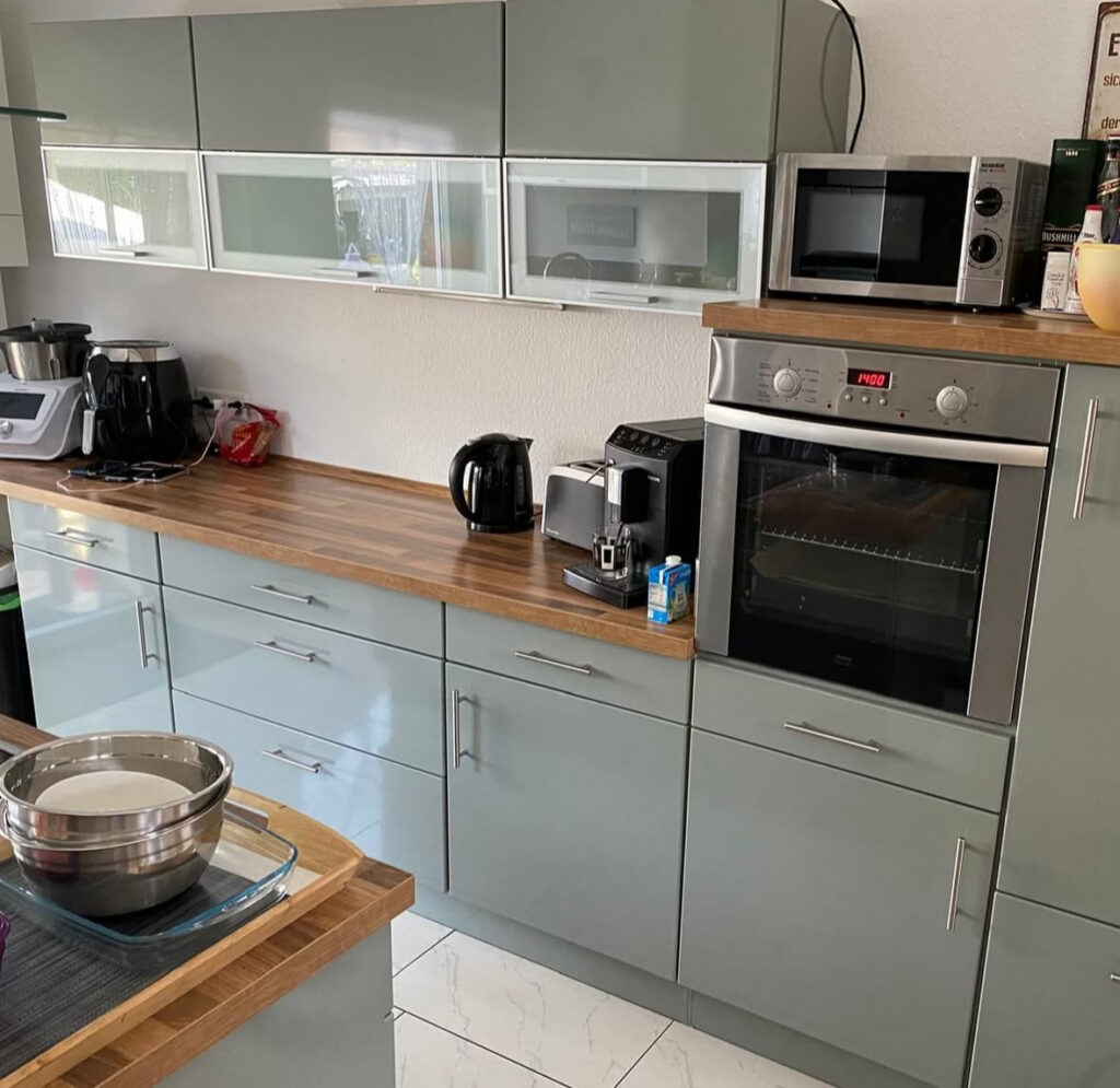 Run of glossy grey upper cabinets and plain backsplash before adding open shelving and better kitchen storage solutions by @thepotthouseno60.