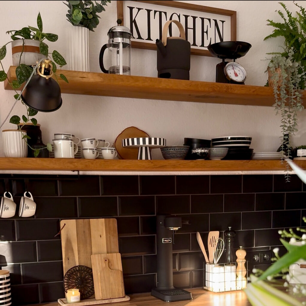 Black tiled coffee bar with warm wood open shelves, neatly arranged mugs and everyday coffee gear turned into stylish storage by @thepotthouseno60.