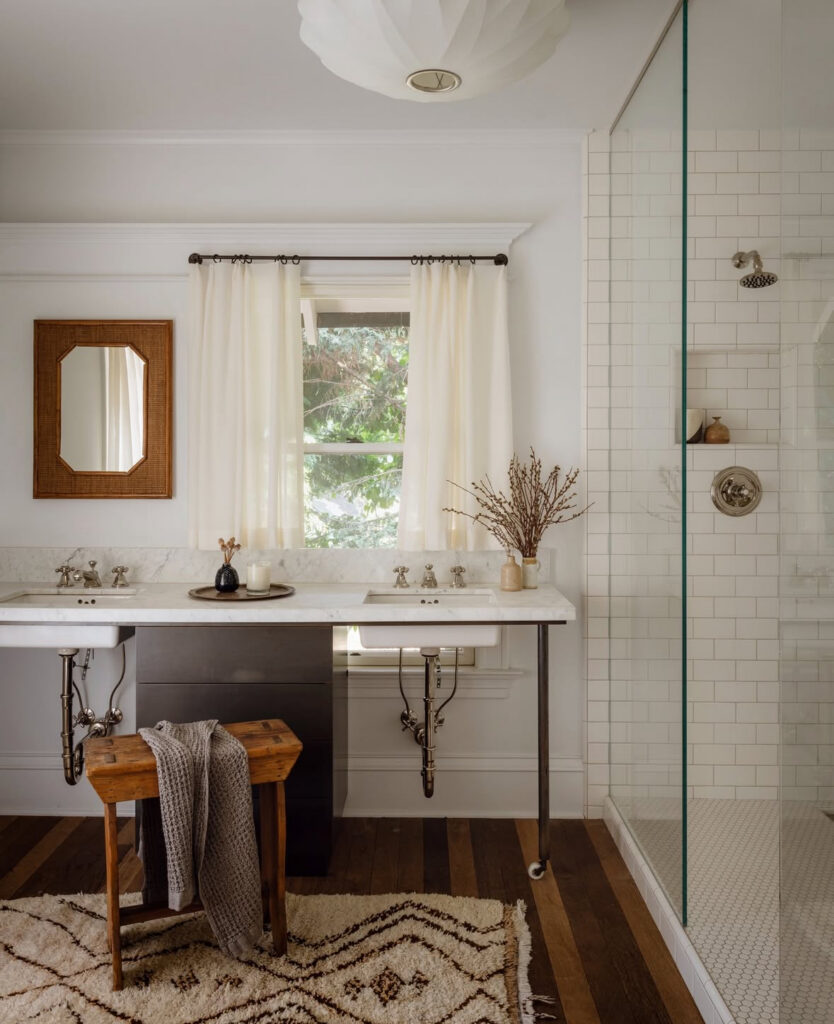 Airy double-sink space with white tile shower and globe vintage bathroom light fixtures above the vanity.