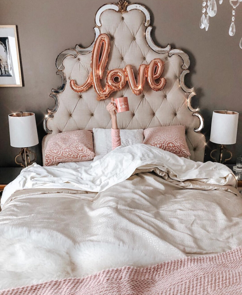 A luxurious bedroom with ornate tufted headboard and rose gold “love” balloons showcasing classic valentines room decor.