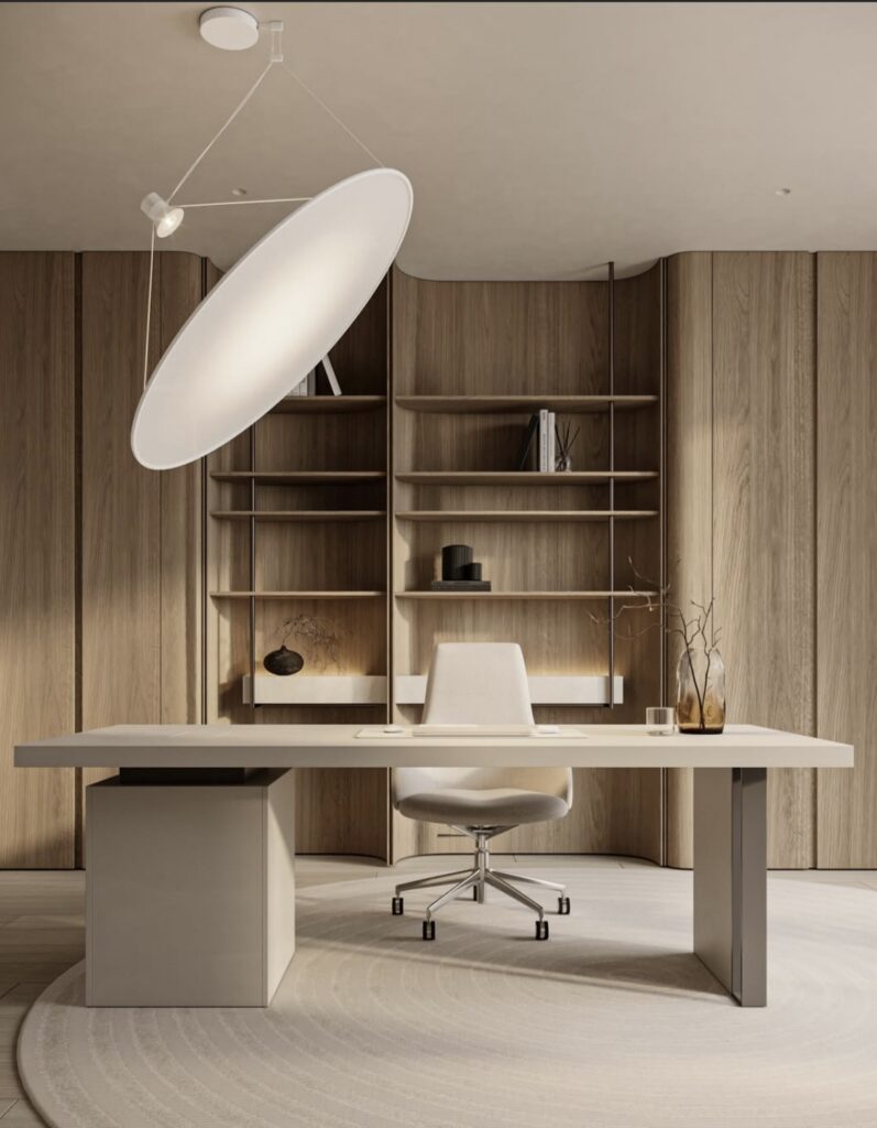 Minimal beige home office featuring a sculptural dish pendant light, pale wood shelves, simple modern desk and neutral swivel chair.