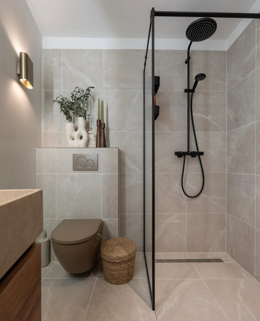 Modern bathroom design with soothing off-white walls, large beige tile, matte black shower fixtures, and a clean, minimal layout.