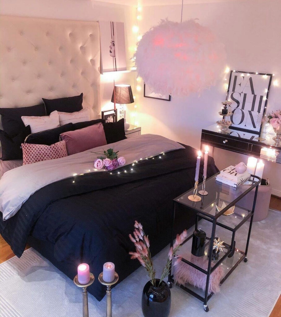 A moody bedroom with black bedding, fairy lights, and pink roses showing romantic bedroom ideas for valentines day at home.