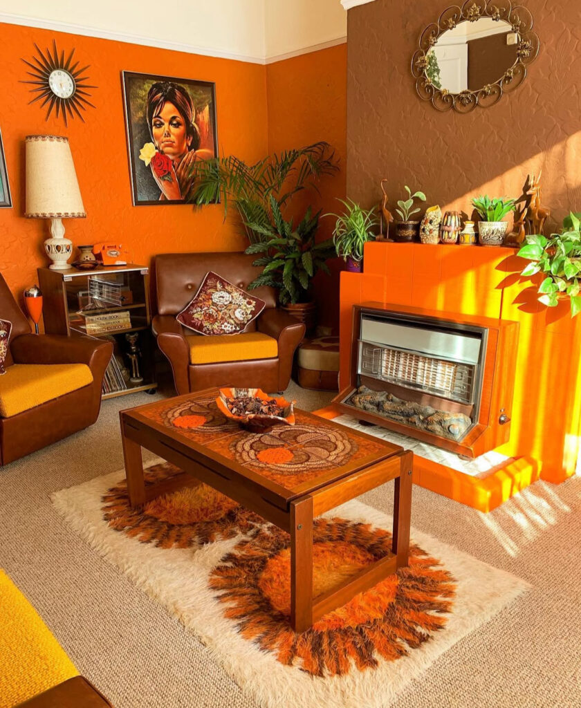 Classic 70s decor living room scene with orange walls, brown accent fireplace, leather chairs and sunburst clock.