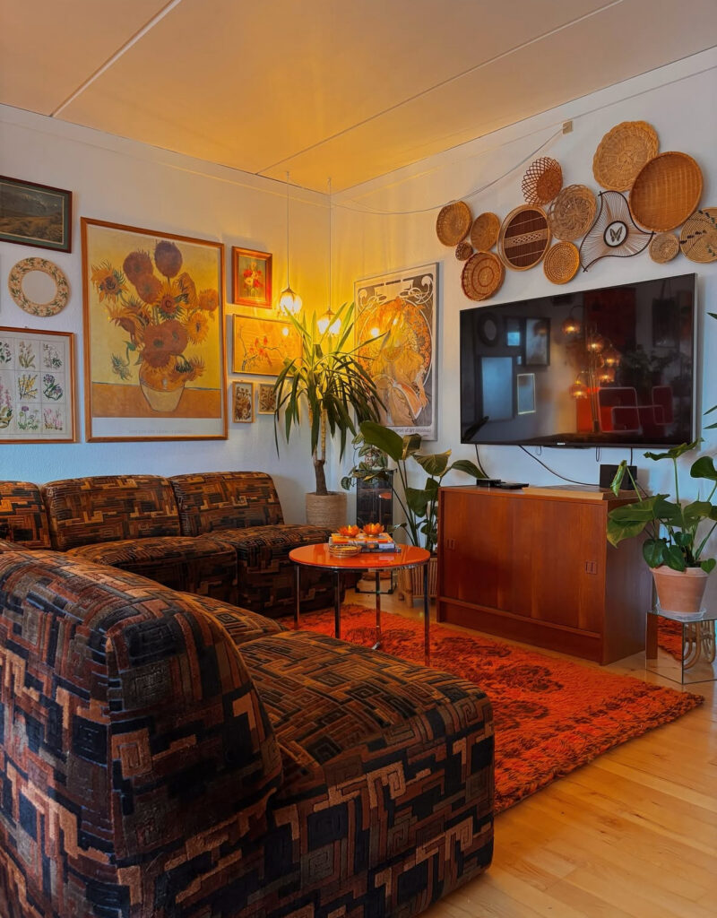 Living room 70s home decor with a patterned sectional, deep orange shag rug, gallery wall and basket display.