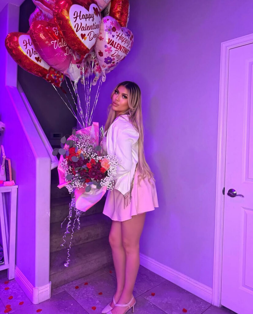 Woman in a pink Galentine’s outfit holding Valentine balloons and flowers for a party-ready look
