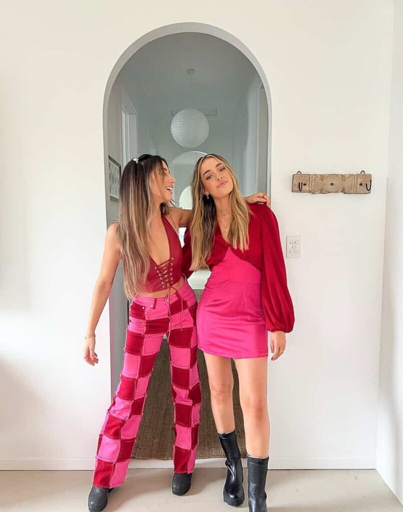 Two women in bold pink Galentine’s day outfits featuring statement pants and a mini dress for a night out