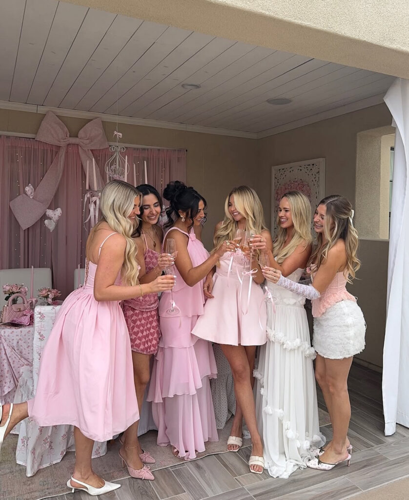 Group of women wearing coordinated pink Galentine’s outfits posing together at a celebration