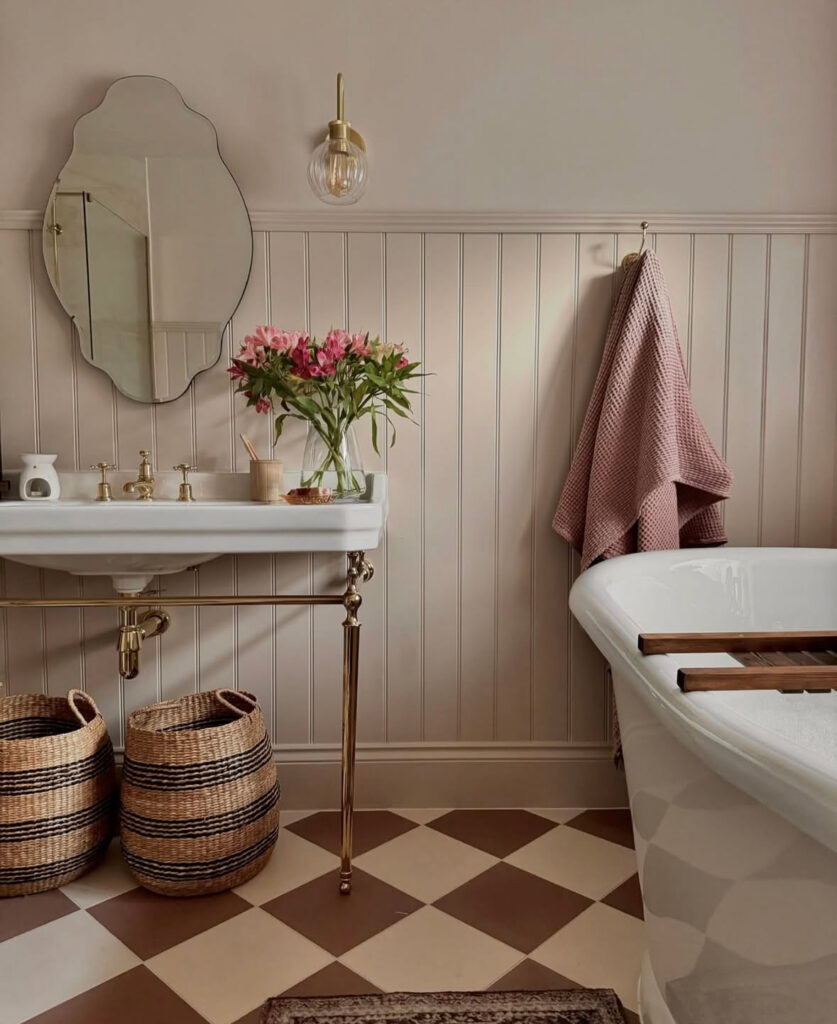 Blush-toned room with brass fixtures and a checkered floor, capturing soft retro vintage bathroom ideas.