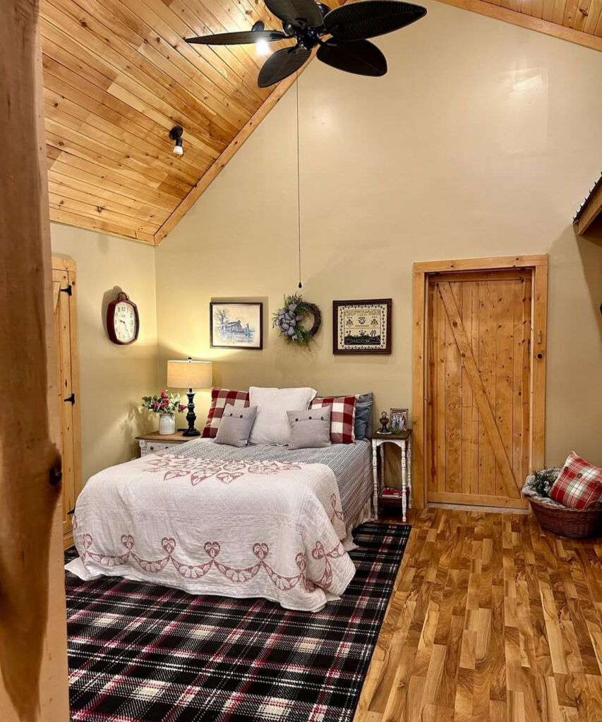 A rustic cabin-style bedroom with wood walls, plaid accents, and heart-embroidered quilt—romantic bedroom ideas for valentines day.