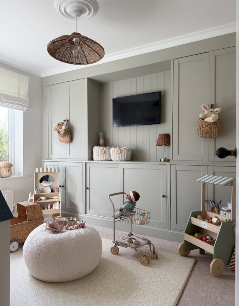 Sage built-in cabinetry wall with a TV and closed storage creating a calm, functional playroom.