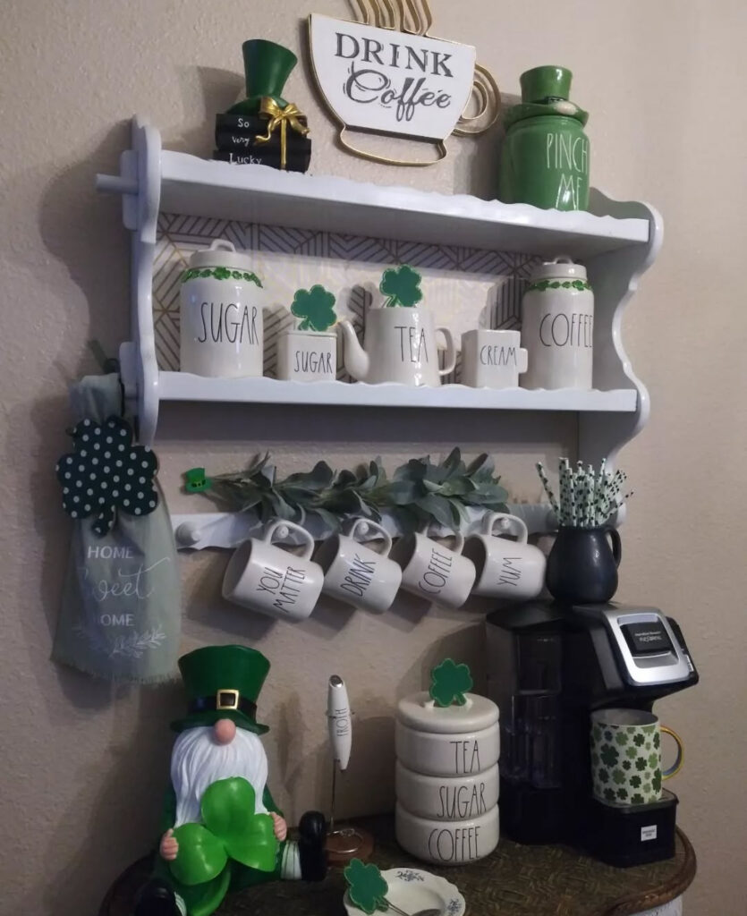 shamrock decor on a coffee bar shelf with mugs, canisters, small clover touches, and a cozy gnome moment.