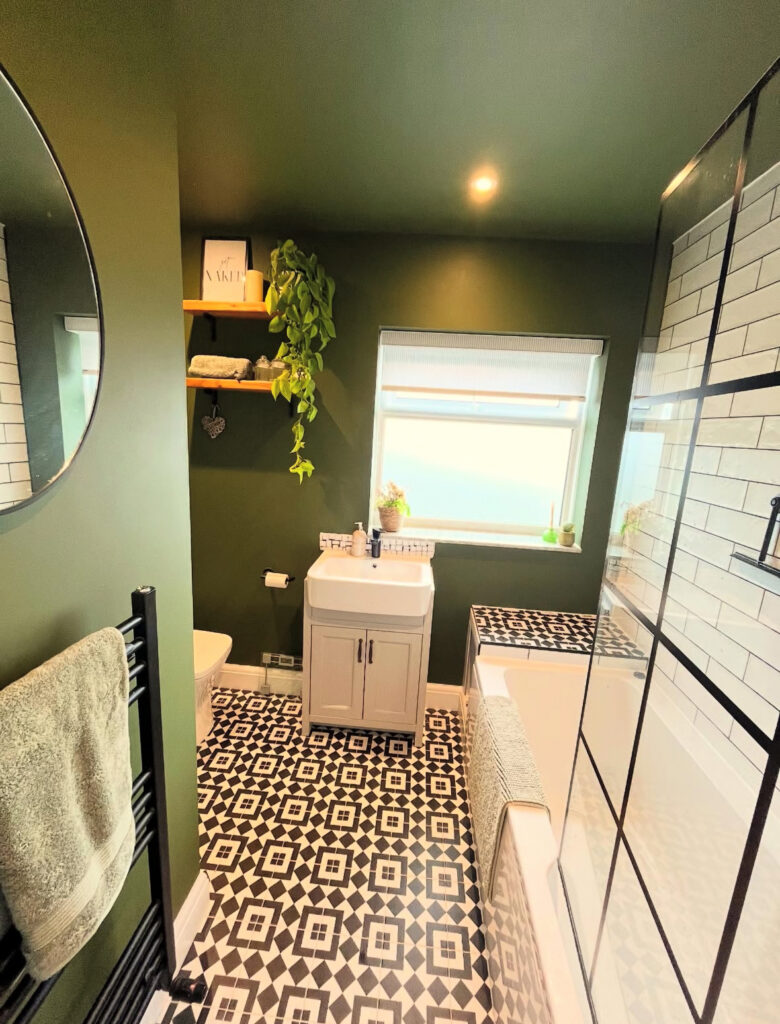 Small bathroom paint ideas using relaxing olive green on walls and ceiling with graphic floor tile and black shower framing.