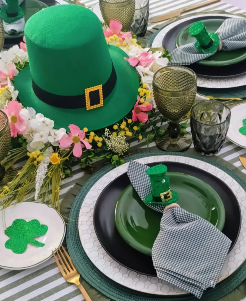 st patricks day party ideas tablescape with a green hat centerpiece, layered plates, textured glassware, and gold flatware.