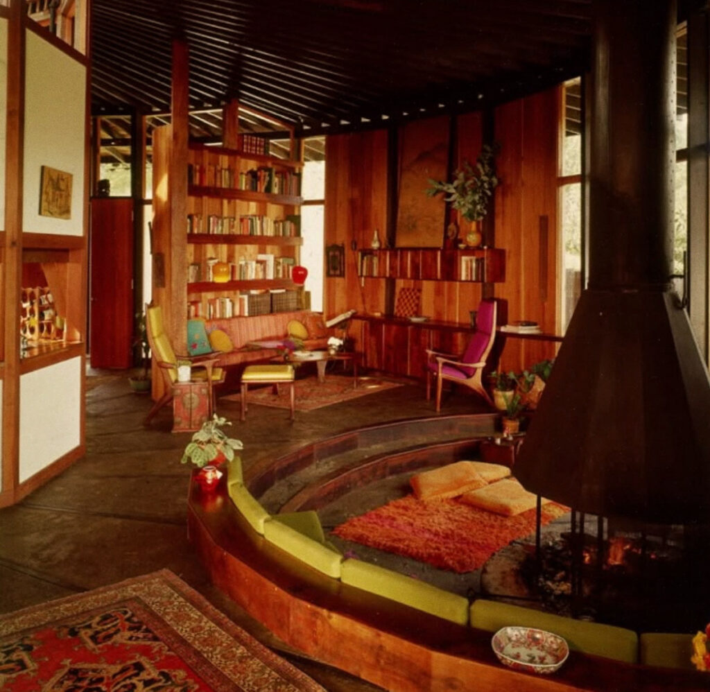 Cozy sunken living room 70s with circular built in seating, central fireplace and warm wood paneling, a classic example for 70s Living Room Decor Ideas.