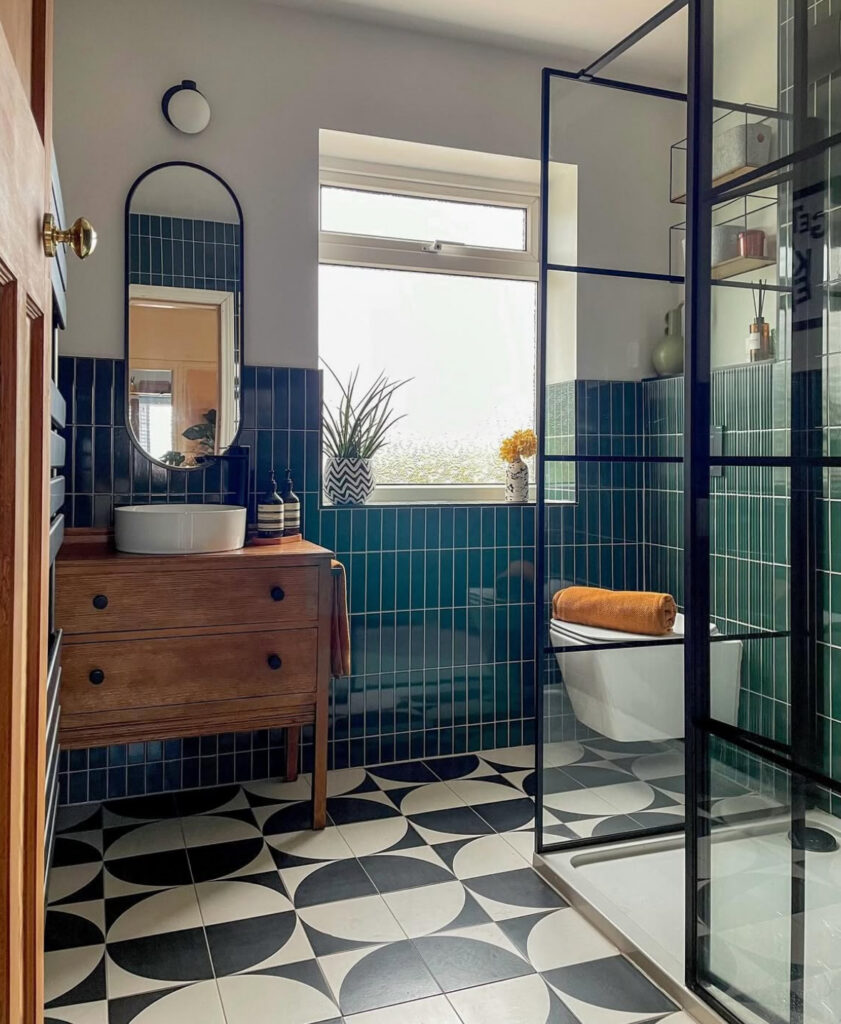 Graphic space combining a wood vanity, bold floor pattern, and teal walls for a fresh vintage green tile bathroom look.