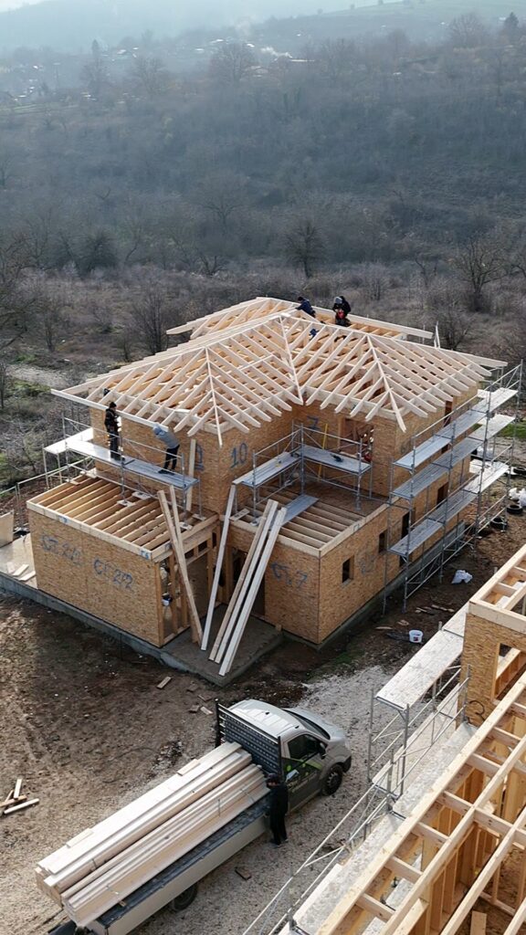 Scaffolding around the house with timber frame roof framing nearing completion