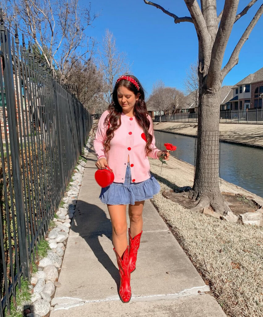 Fun Valentines Day outfit idea: pink cardigan with a denim mini skirt and red cowboy boots (sweet + bold).