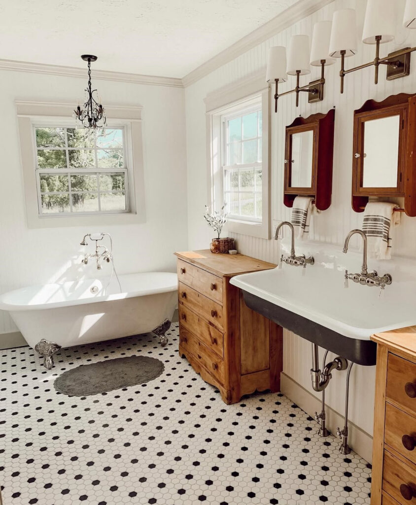 Bright farmhouse vintage bathroom tile with black and white hex floor, clawfoot tub, and wood cabinets.