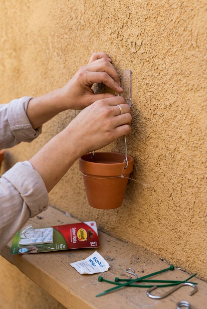 Installing balcony wall decor using outdoor-rated Command hooks and lightweight hanging planters on a rental balcony